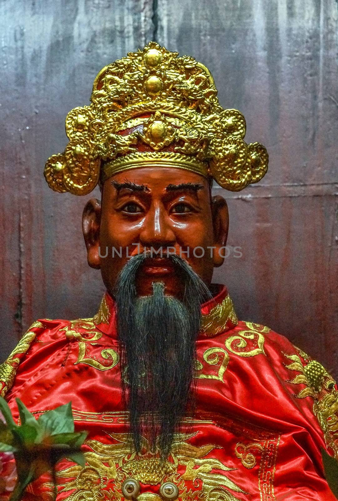 Vietnam Hanoi. Close up of bearded face with decorations in gold and red.
