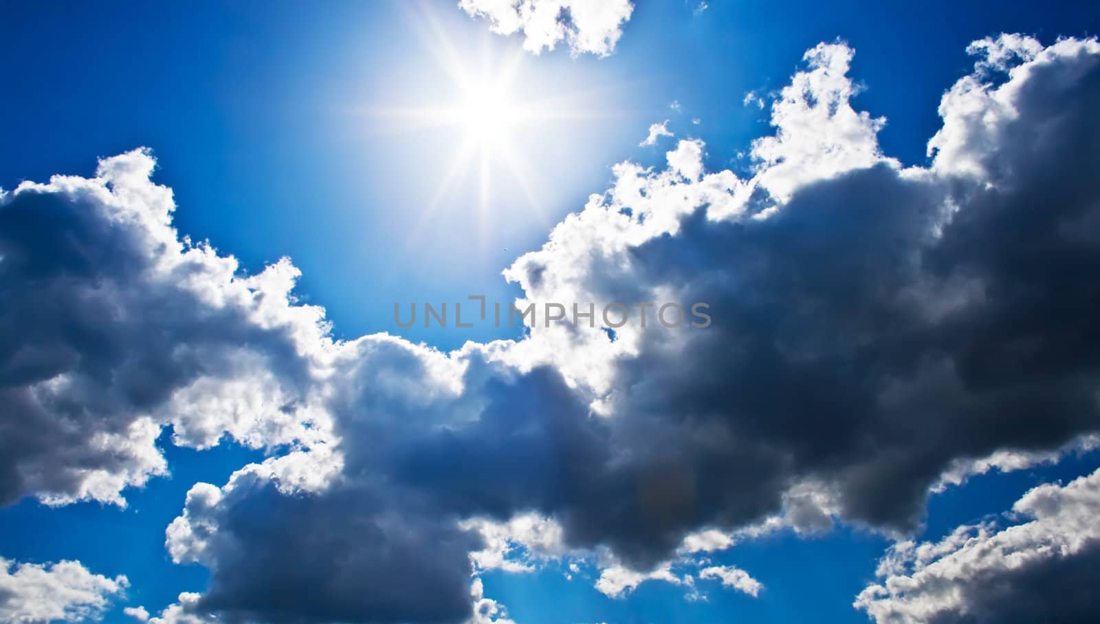 Bright sunrays in a blue cloudy sky