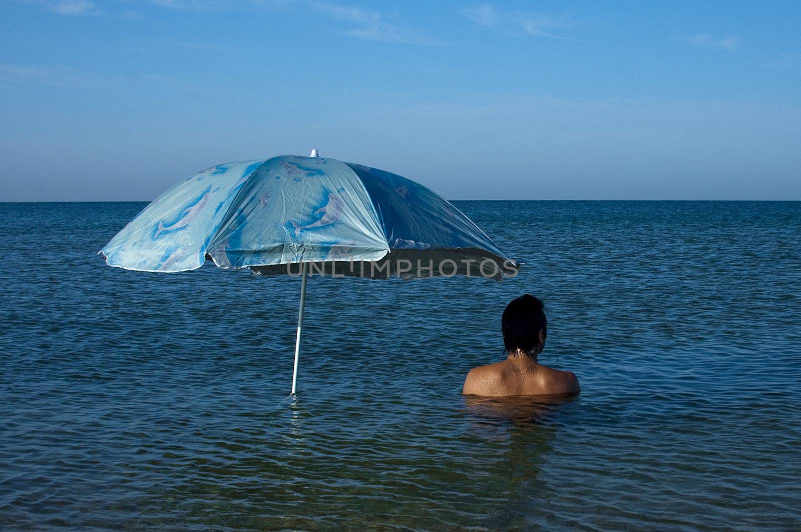 man under blue umbrella in sea water
