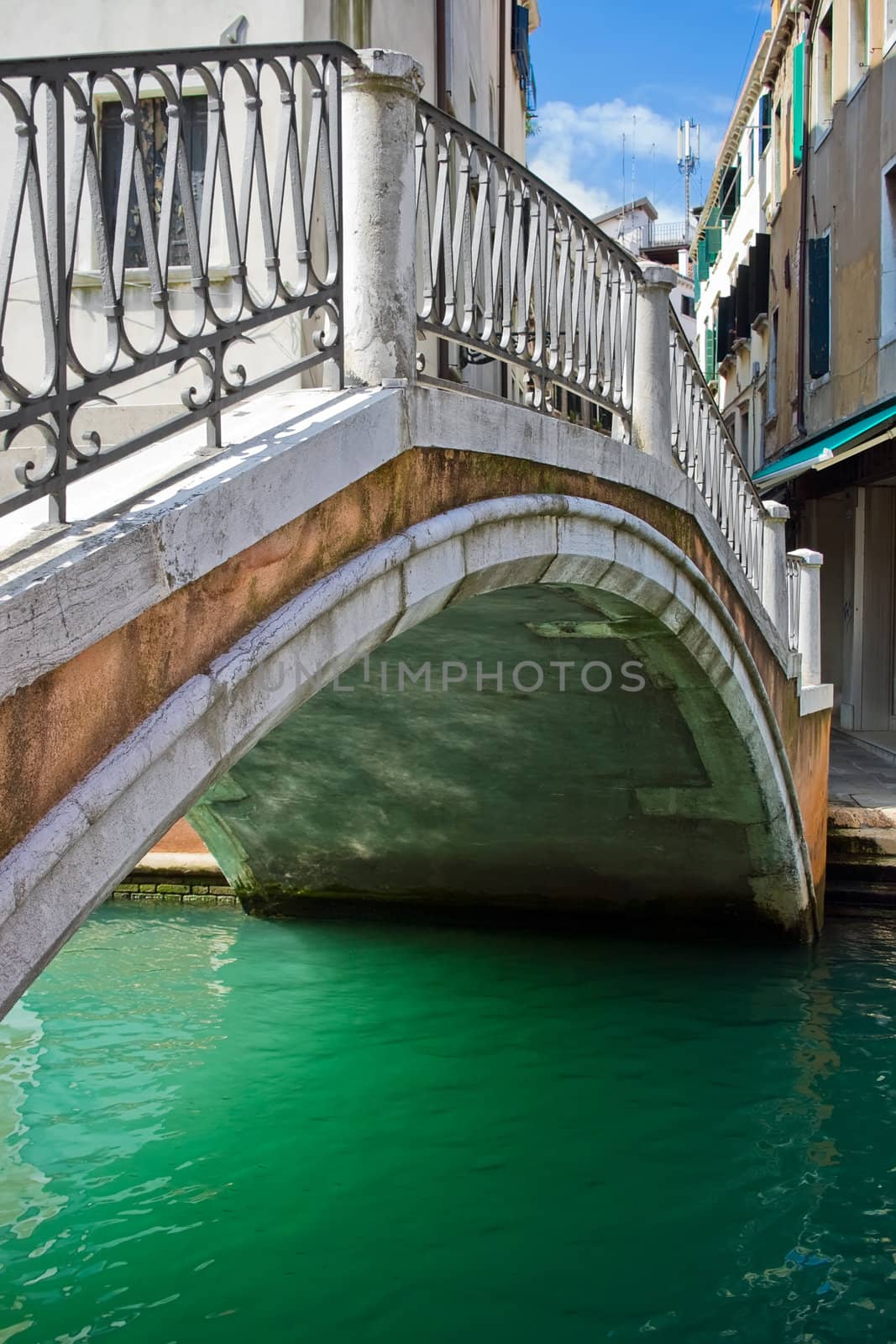 Nice stone bridge over green water of a venetian canal, Italy