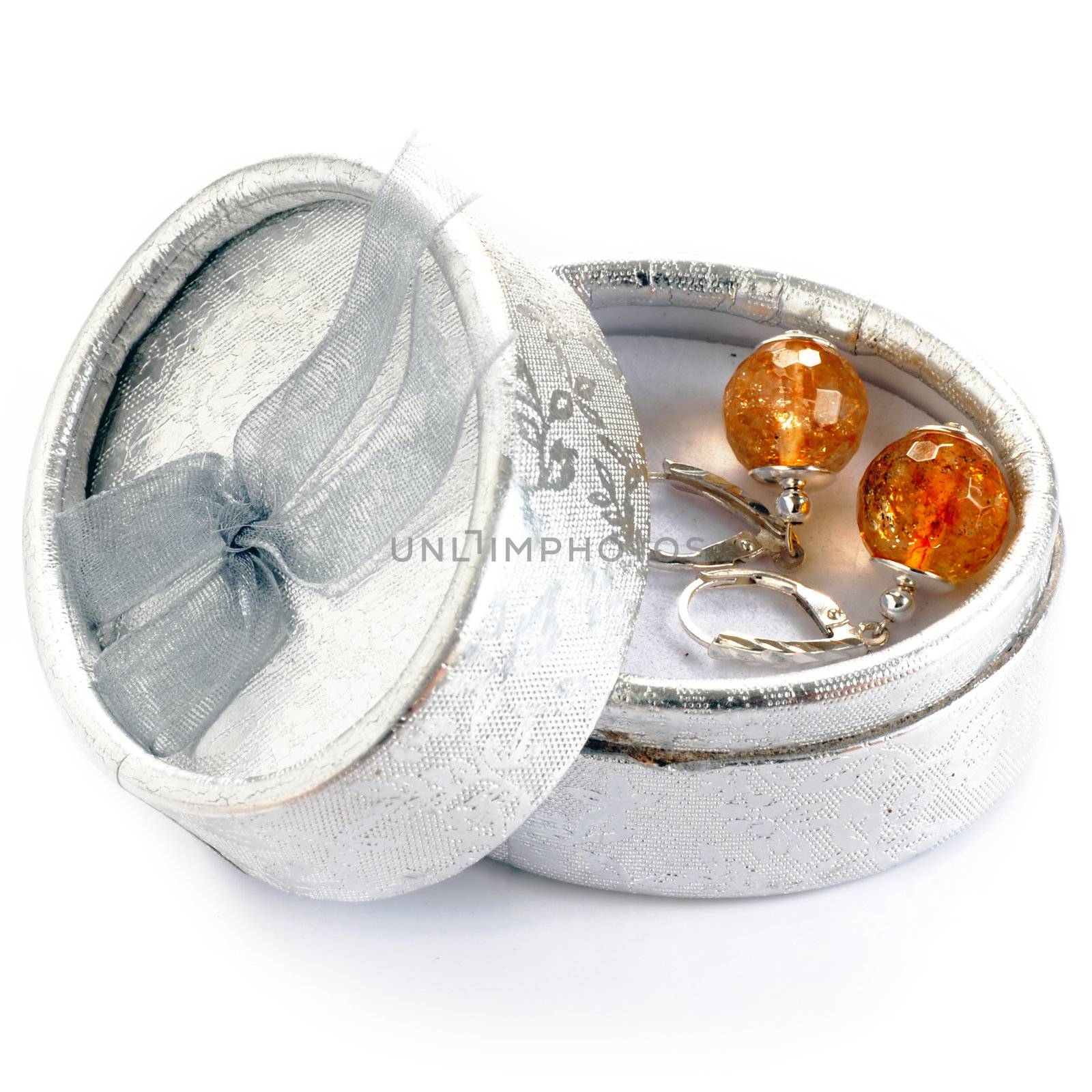 closeup of silver earrings in silver gift box over white background