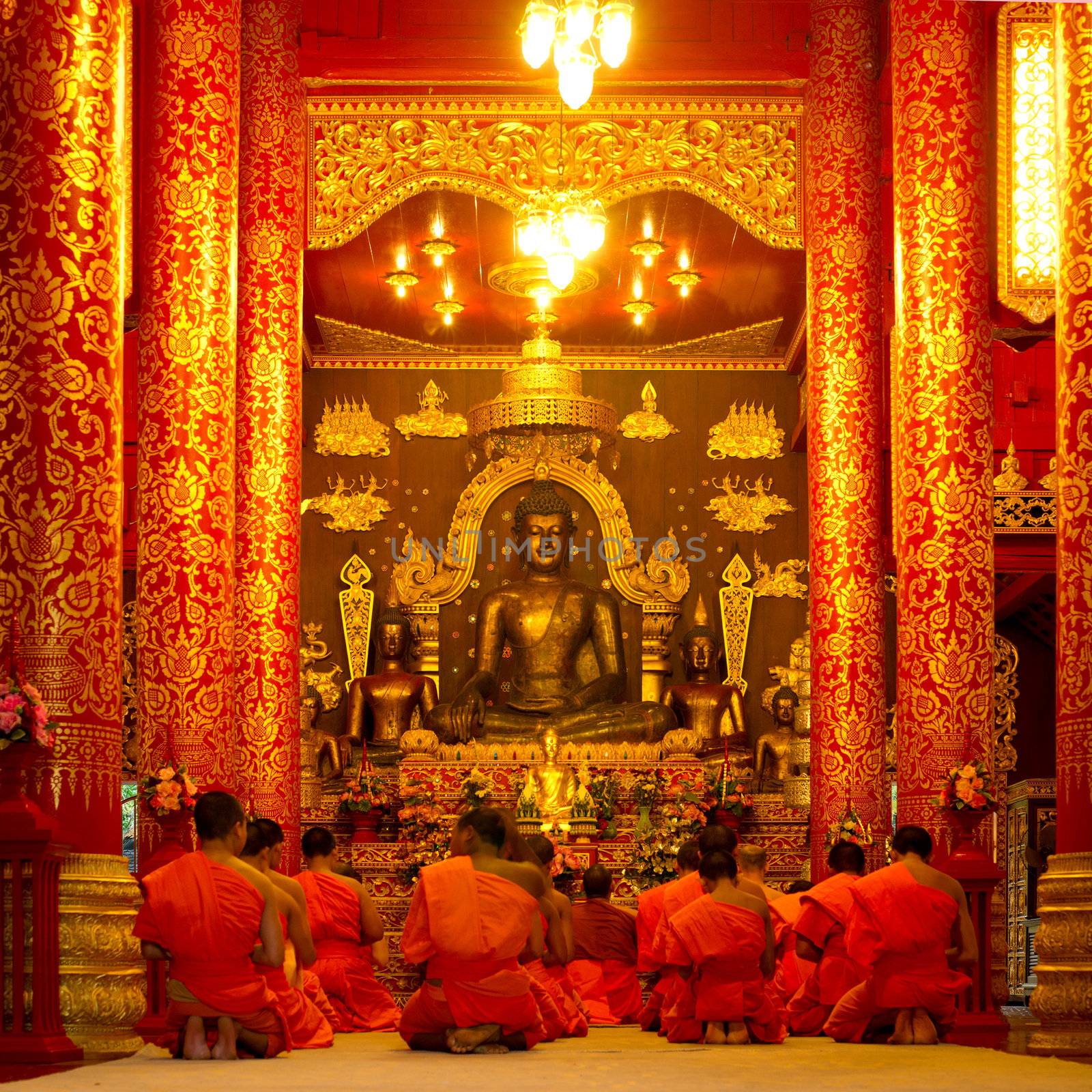 Group of buddhist monks sitting in the temple and praying