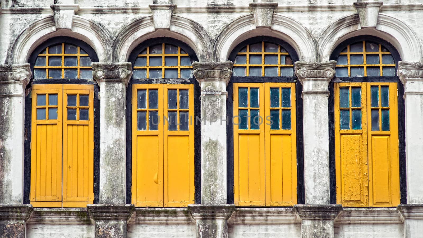 Four wooden yellow windows in old building with arches and columns
