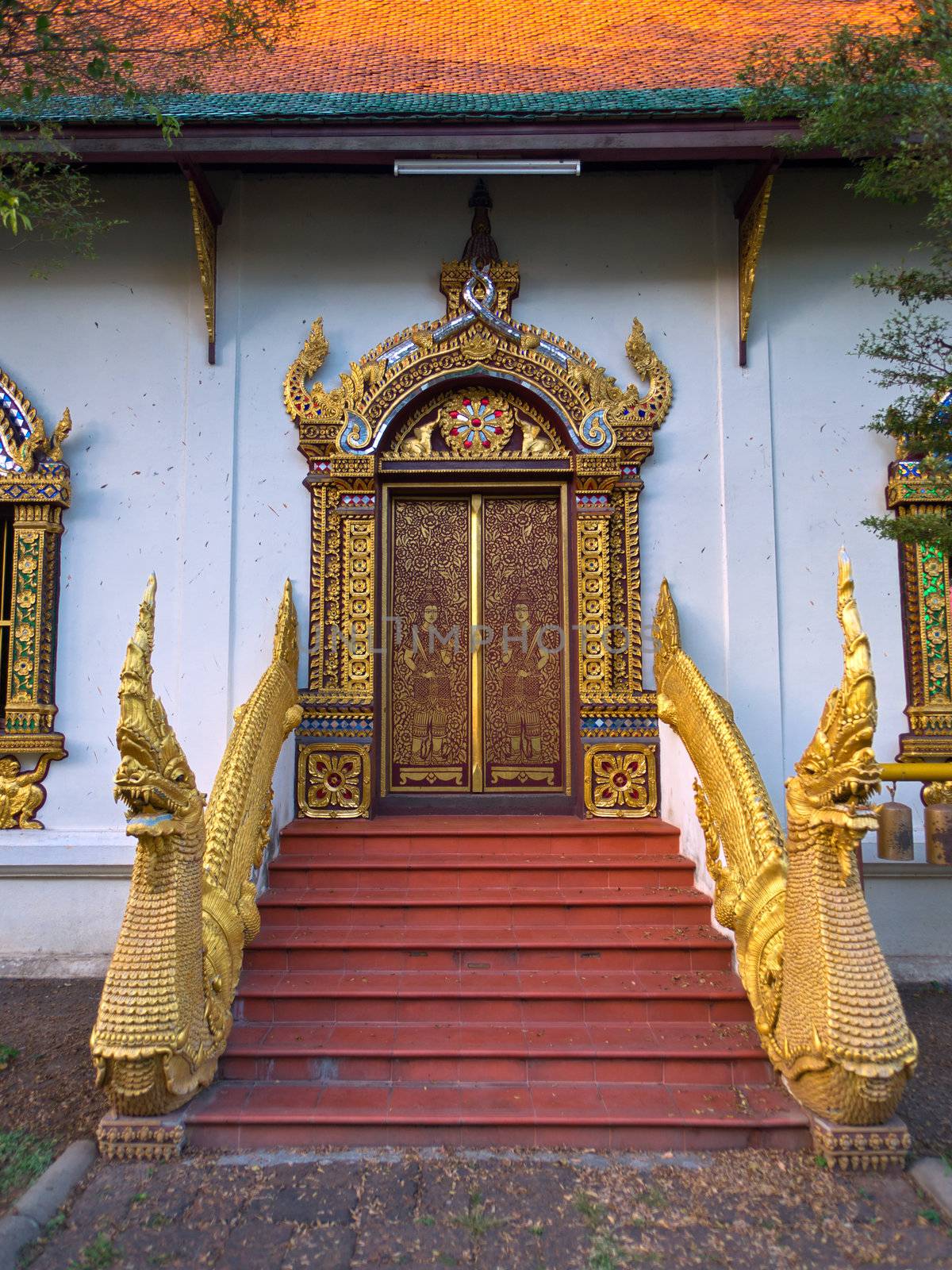 Golden dragons in front of carved doors of asian temple, Wat Chiang Man, Chiang Mai, Northern Thailand