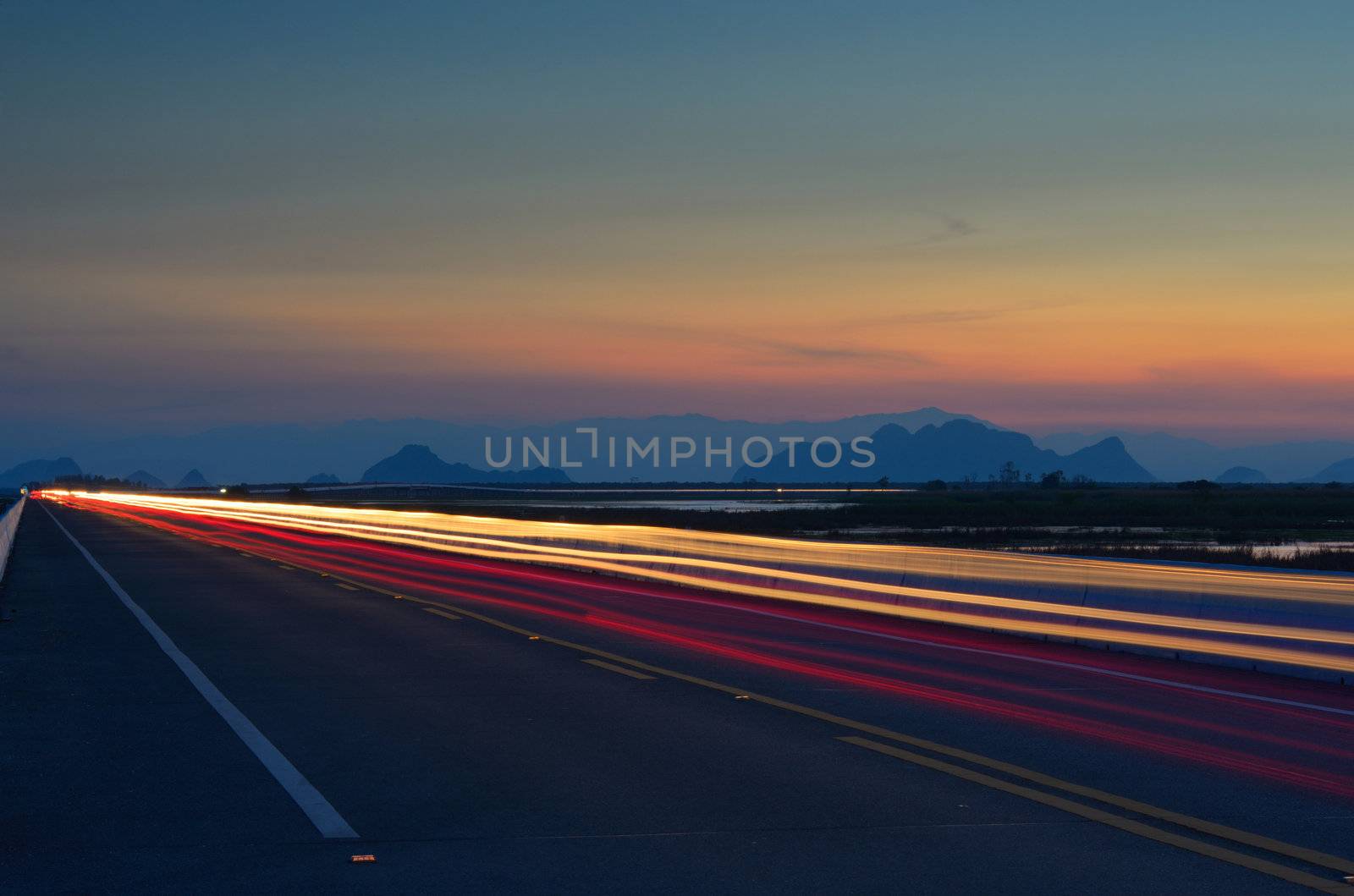 the light trails on the street with sunset and mountain background