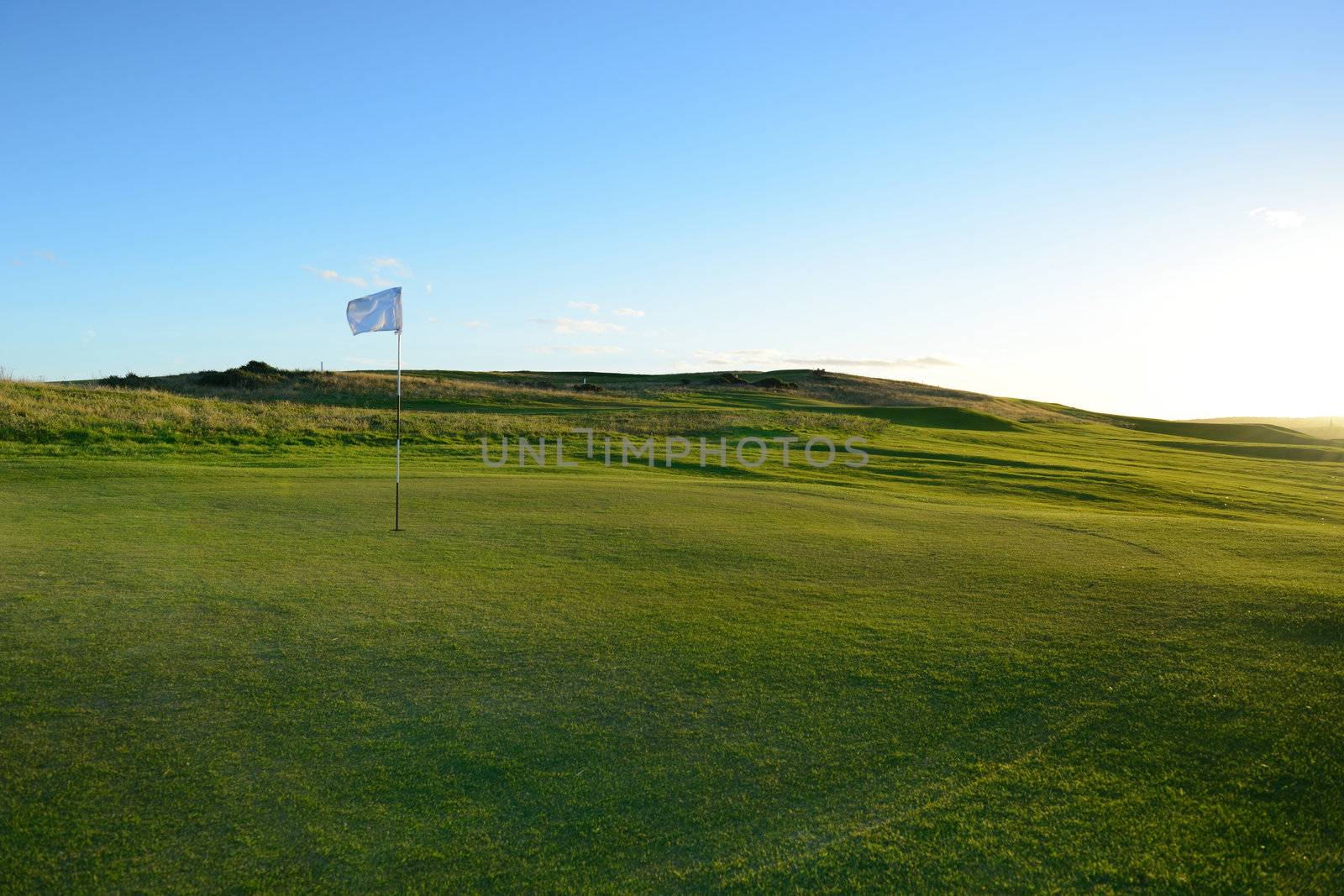 The flag is on the nice green golf course .