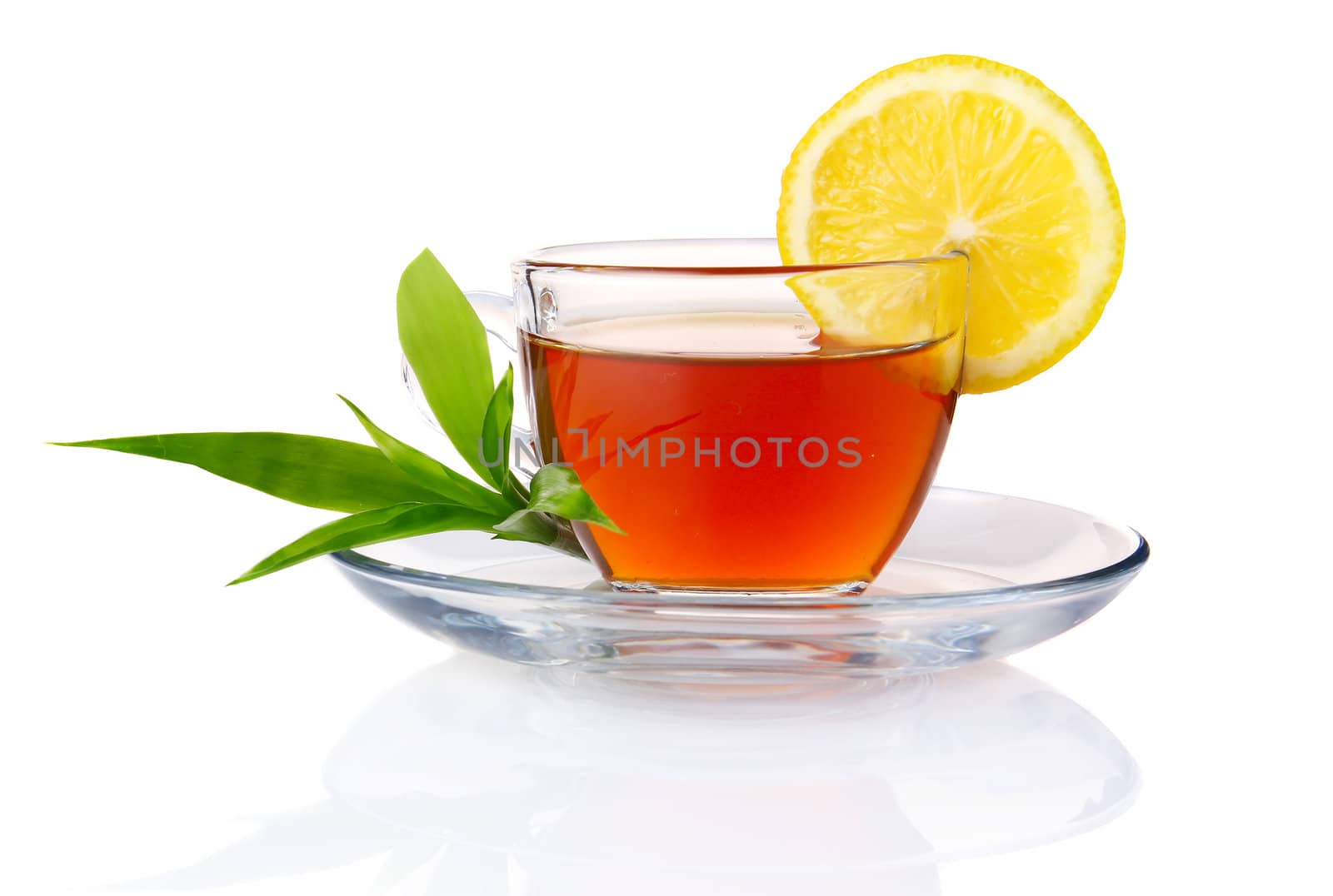 Cup of black tea with lemon and green leaves isolated on white background