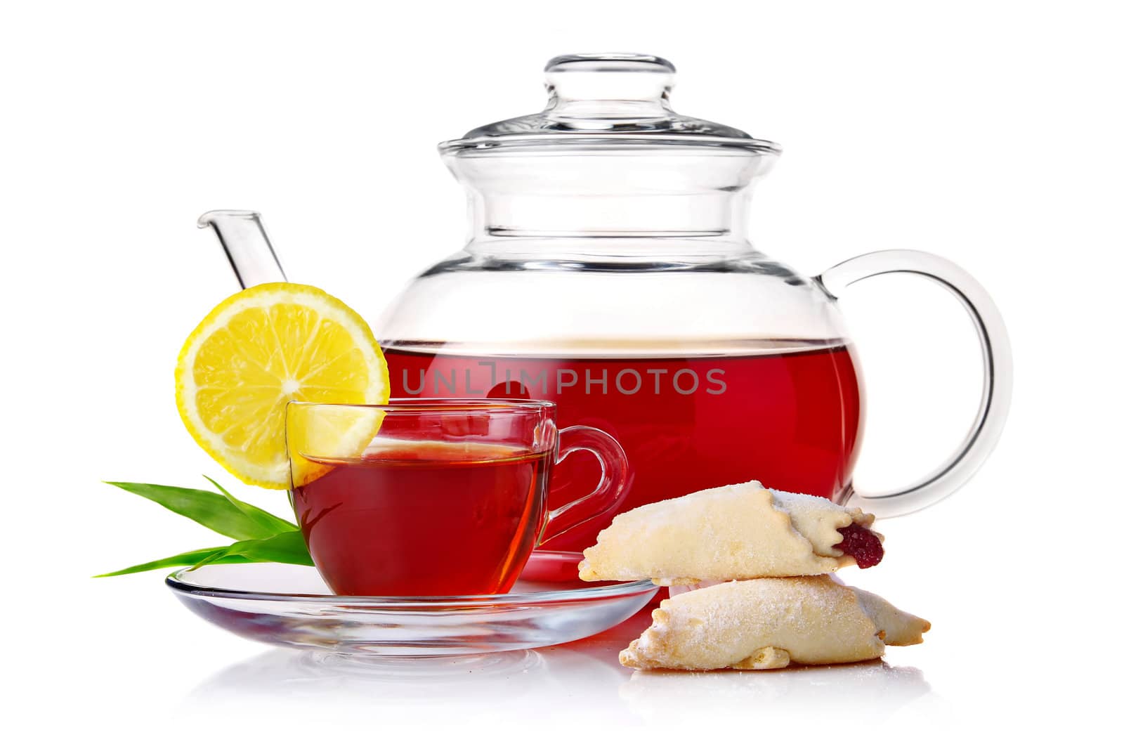 Teapot and cup of black tea with crescent and lemon slice isolated on white background
