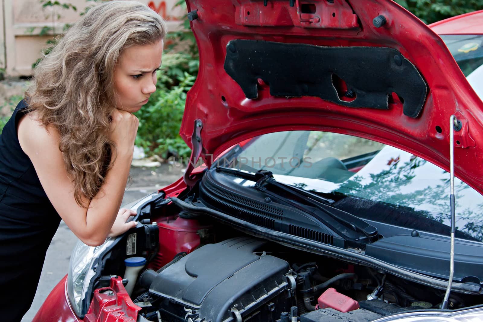 Beautiful young woman near the broken car