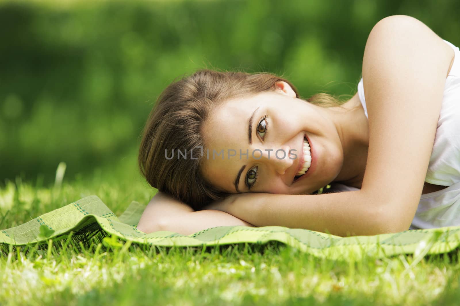 Young smiling woman laying on the grass 