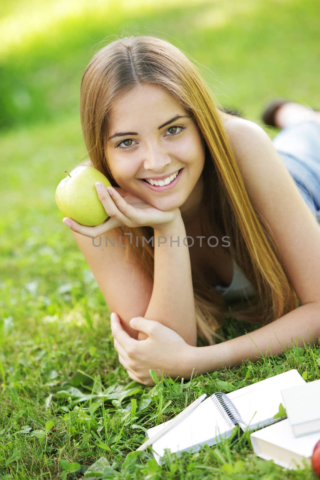 Young smiling woman outdoors holding an apple