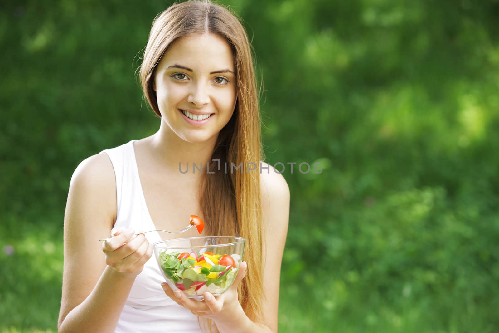 Portrait of happy beautiful young woman eating vegetable salad