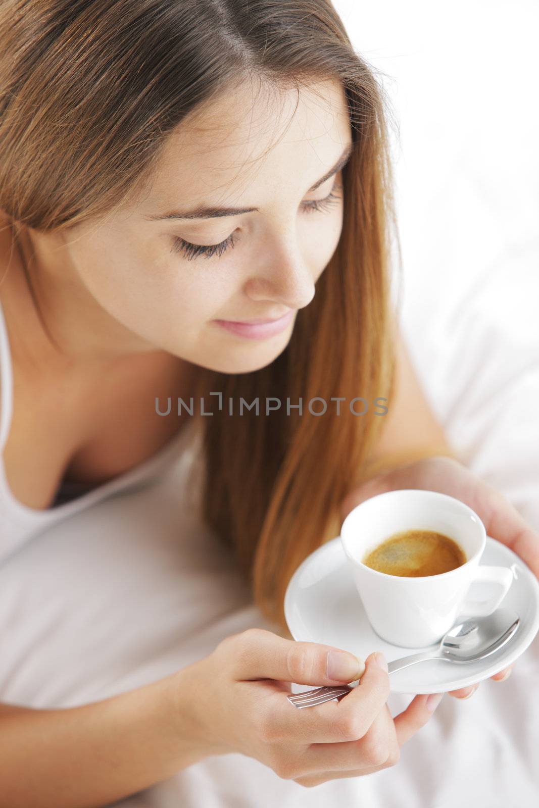 Beautiful young woman in bed drinking cofee in the morning.