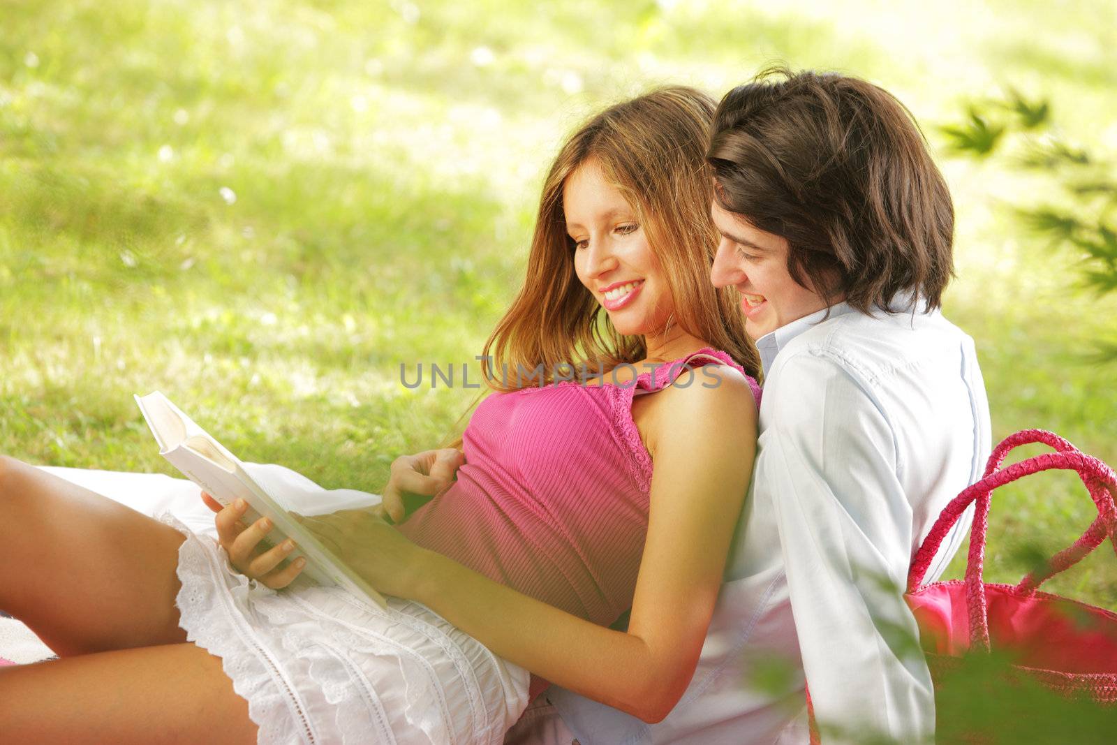 a young couple read a book together in the park