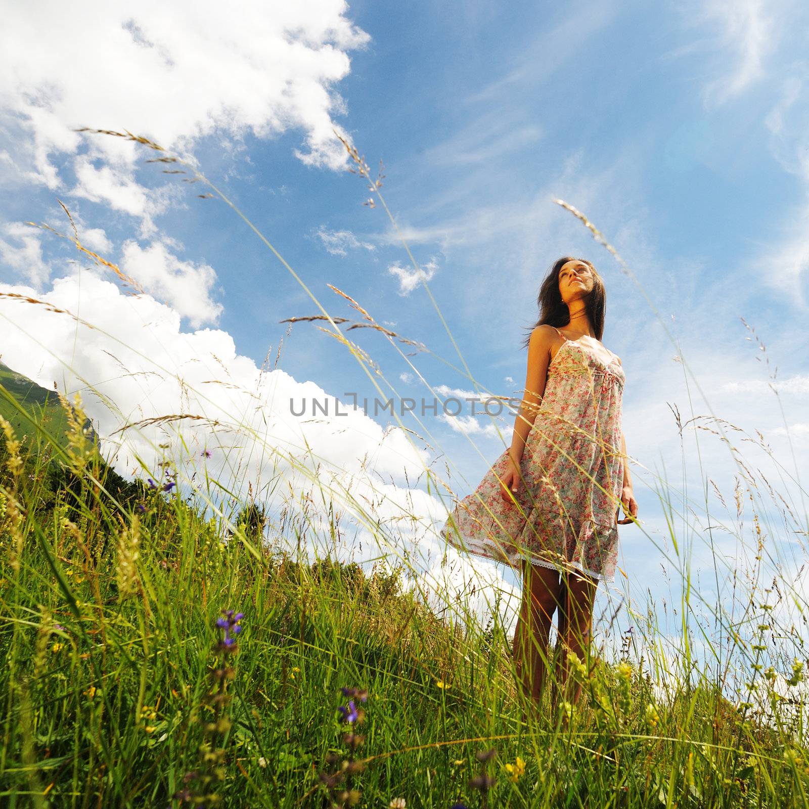 a young woman smiling in the midst of a green lawn, she looks at the sky, so carefree