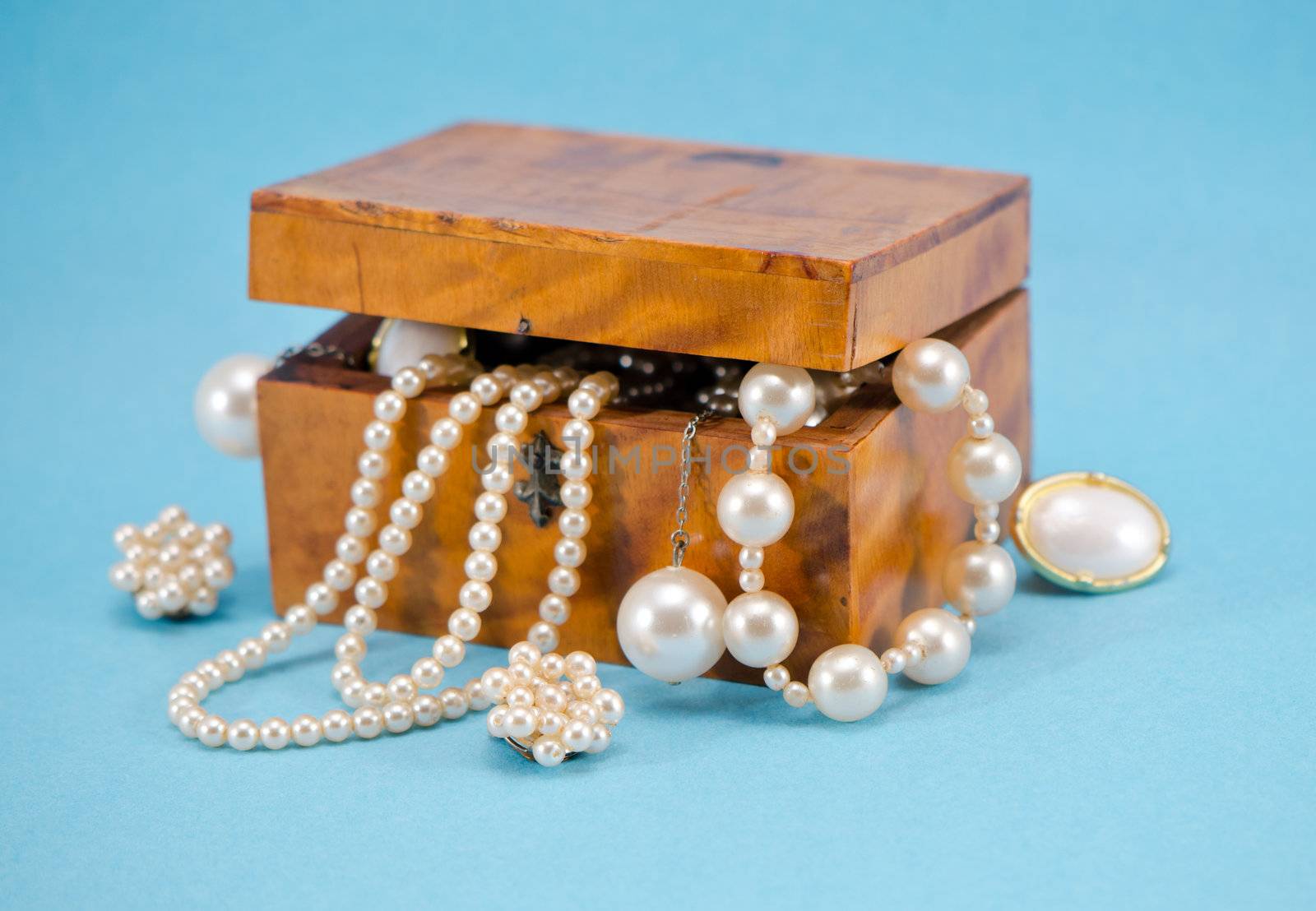 Pearl jewelry beads necklace earring defocus in retro wooden box on blue background