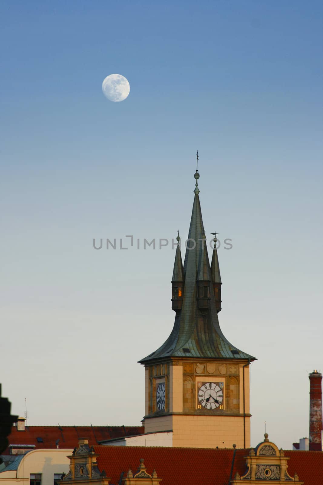 Medieval tower with clock and moon on evening sky in Prague city