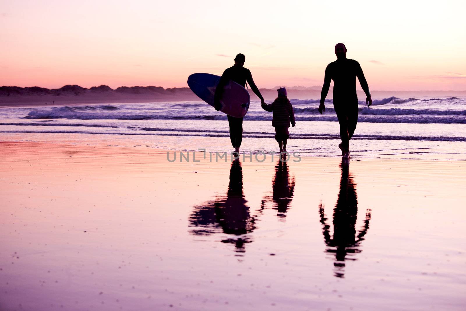 Female surfer and her familly walking in the beach at the sunset