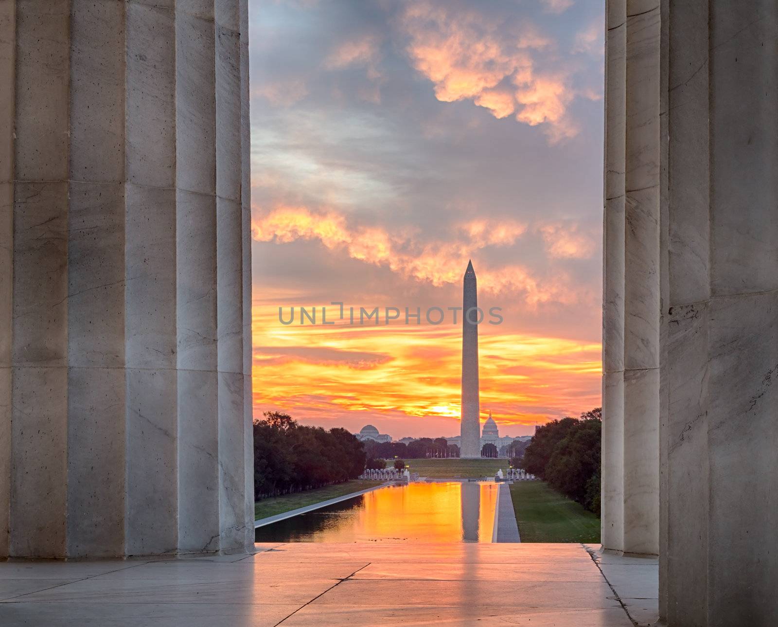 Bright red and orange sunrise at dawn reflects Washington Monument in new reflecting pool by Lincoln Memorial