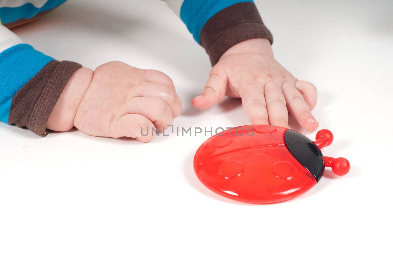 Shot of baby hands and toy on light background