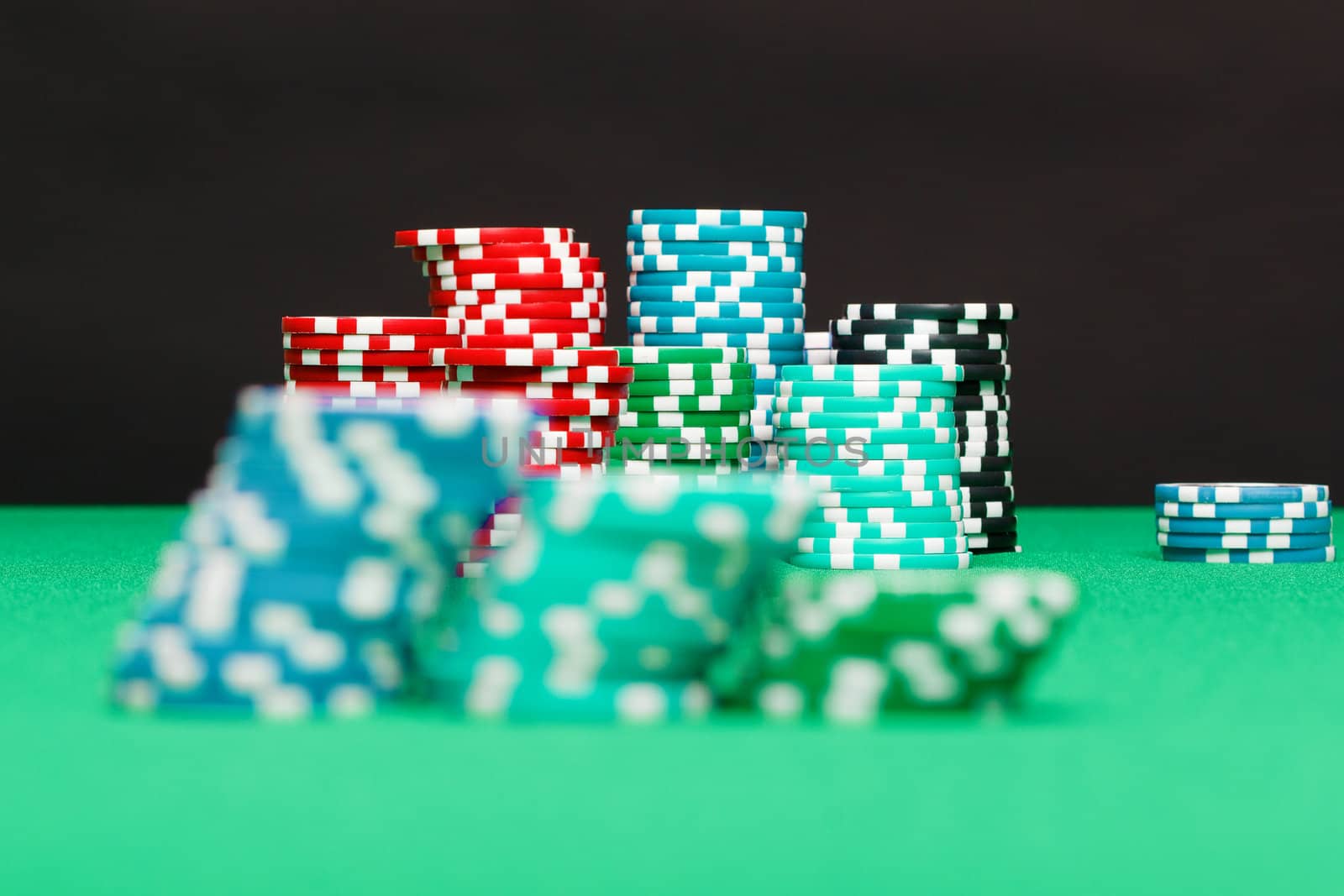 pile of playing chips on the green table on a black background