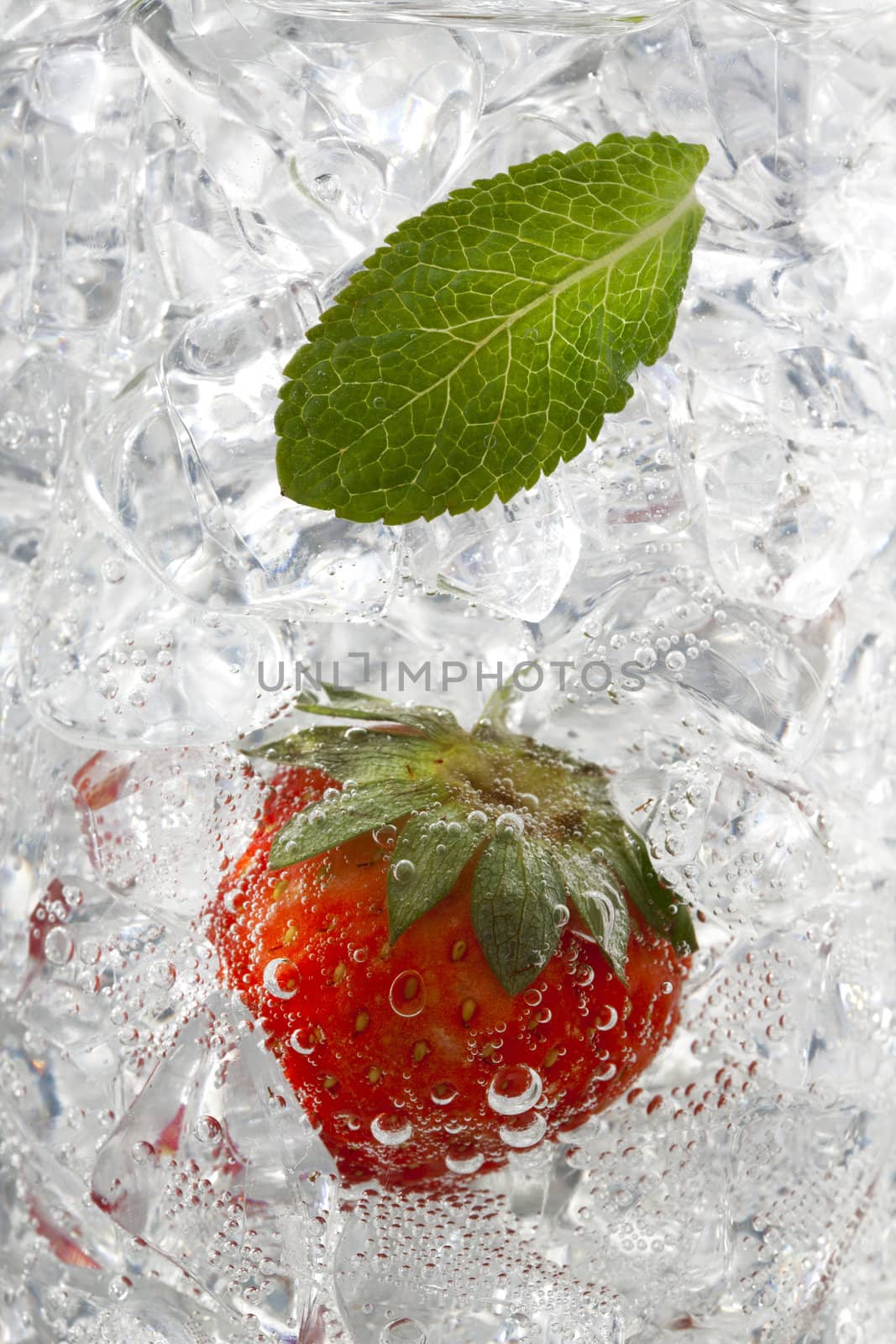 Glass of ice cube with peppermint and strawberry isolated on white background