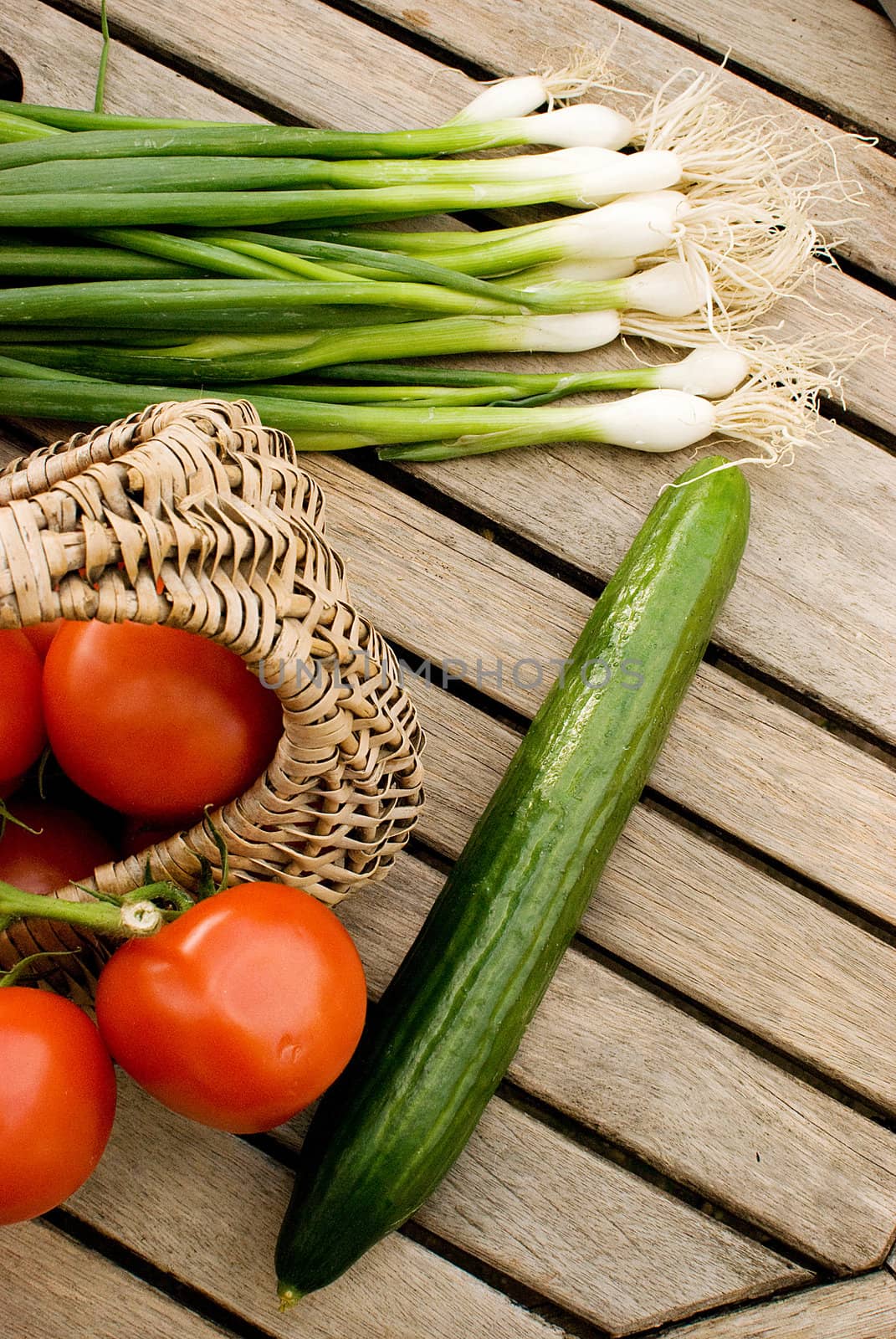 fresh vegetables tomatoes cucumber and green onion in basket over wooden table