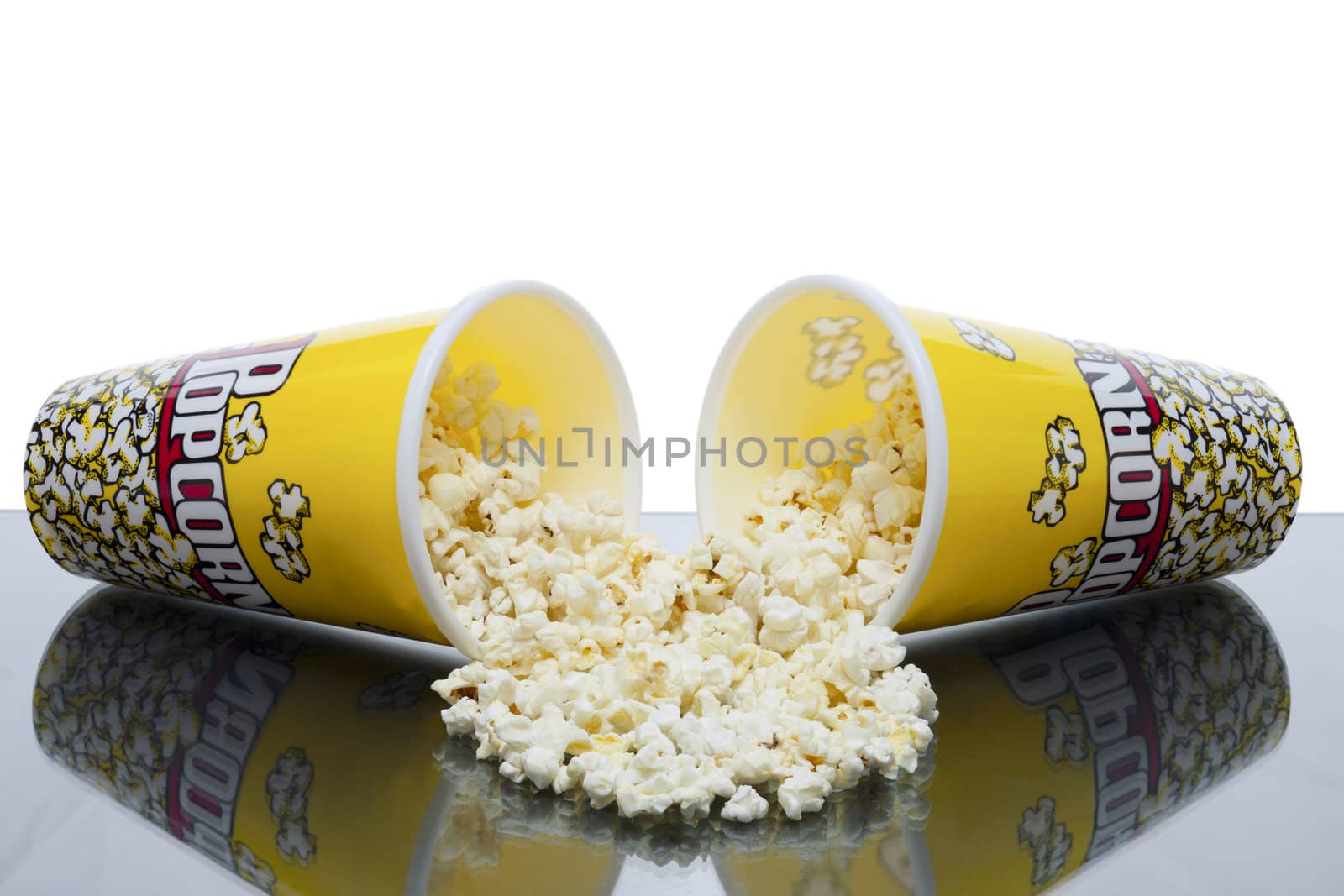 two cups of spilled popcorn with white background