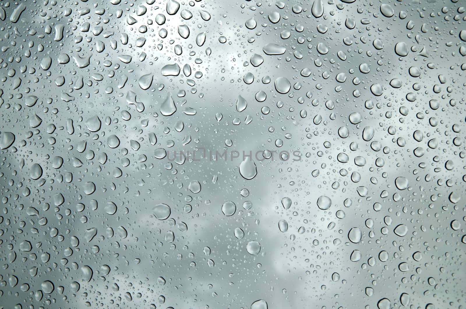 background image of rain drops on glass with a bright sky behind