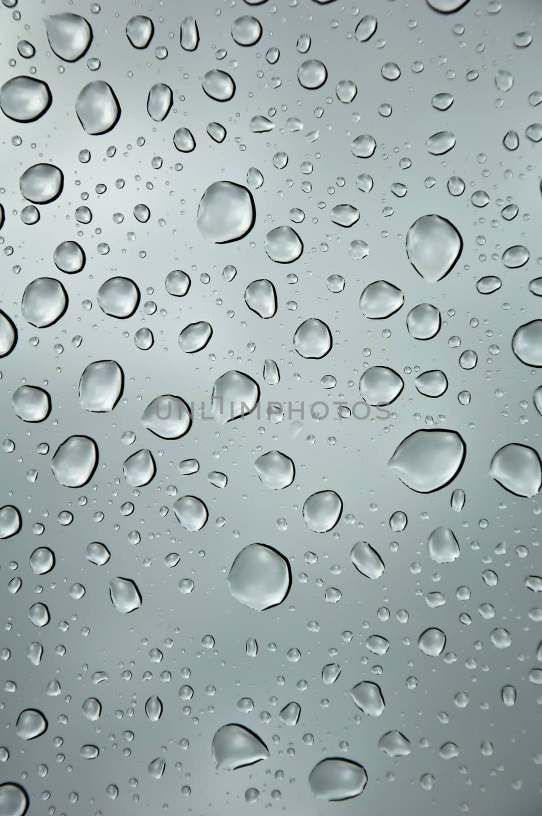 background image of rain drops on glass with a bright sky behind