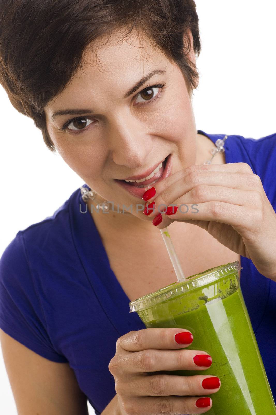 Beautiful woman with manicured nails sips a green smoothie