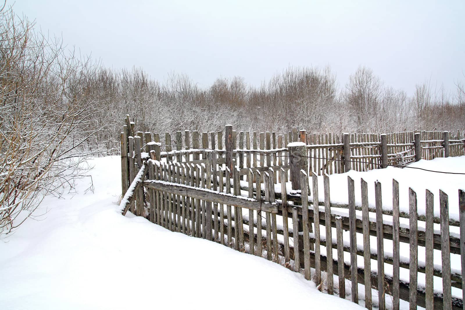 old wooden fence on winter snow