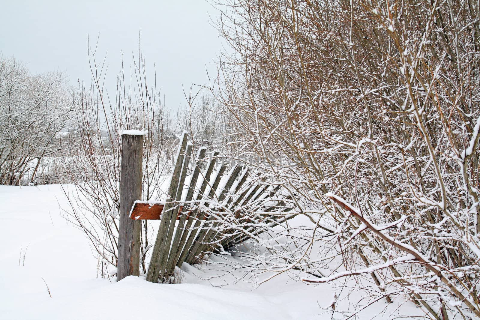 old wooden fence amongst white snow