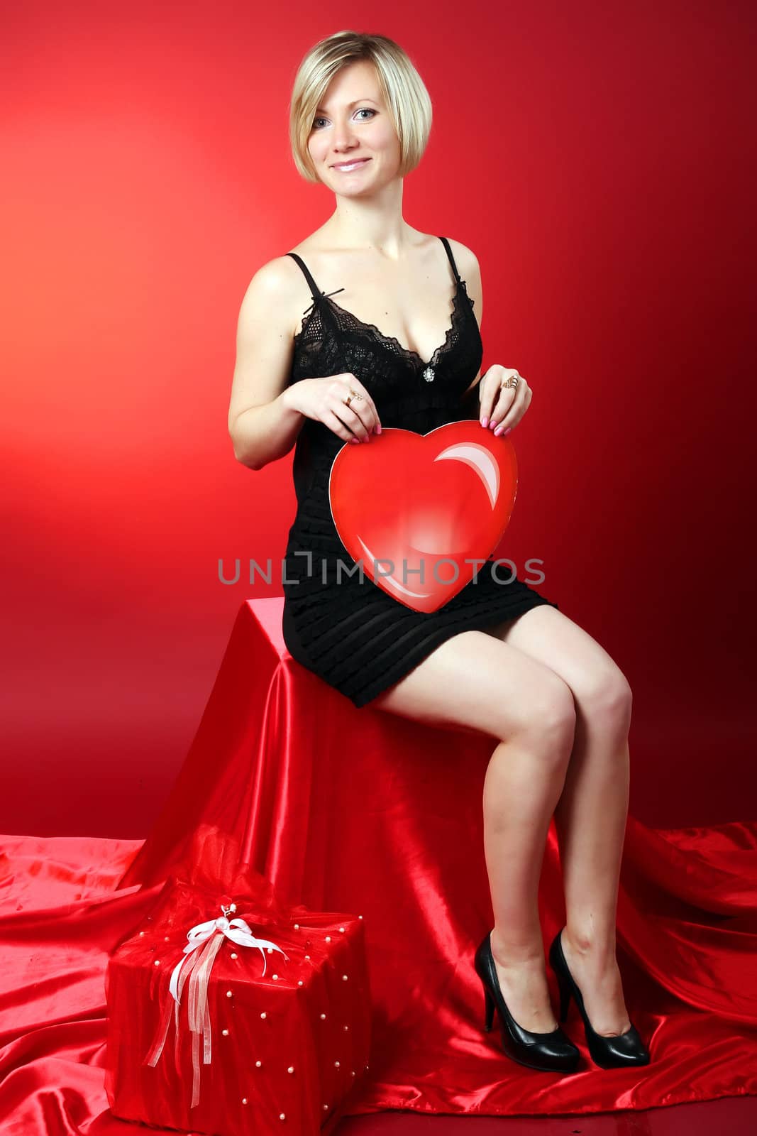 Young beautiful blonde girl hugs a big heart. Feast of St. Valentine's Day. 