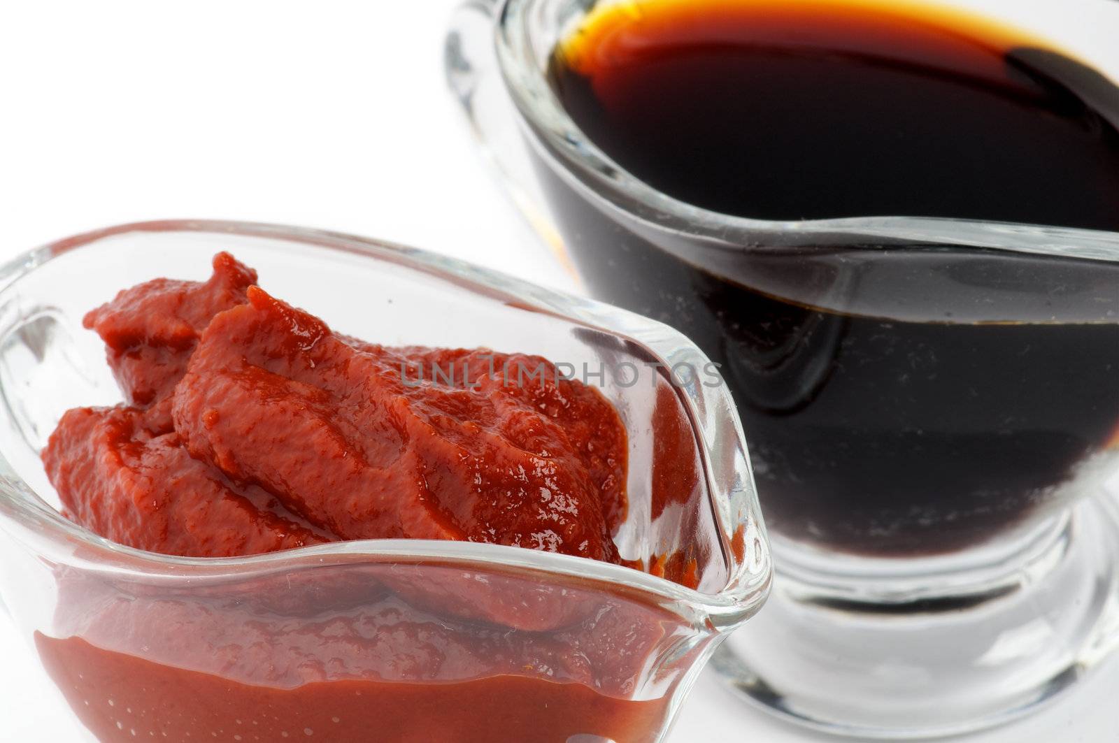 Ketchup and Soy Sauce in Glass Gravy Boat close up isolated on white background