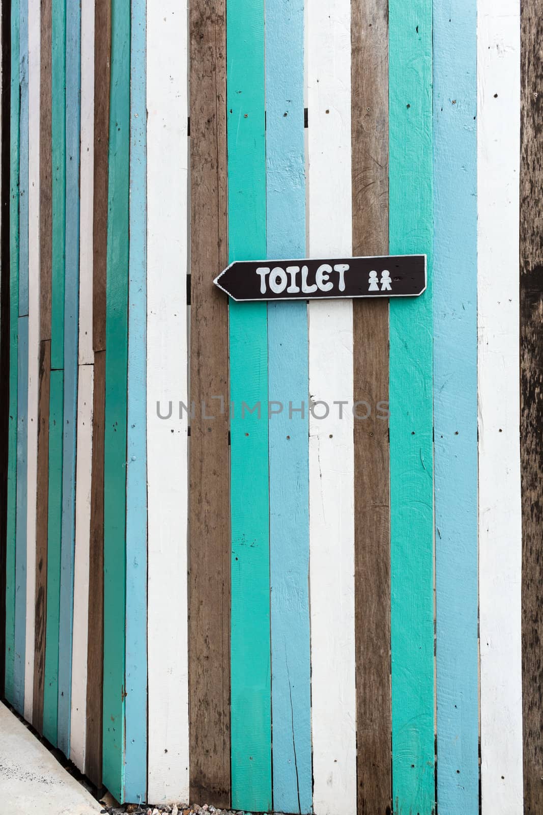 Toilet signposts on colorful wooden fence.