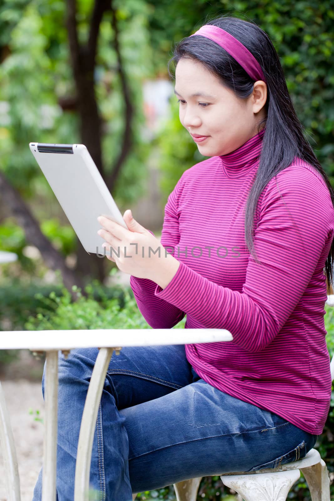Smiling young woman using tablet PC for working in garden