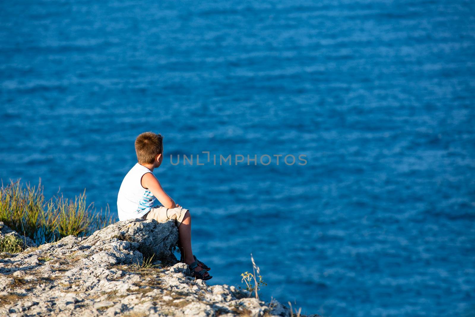 Young kid watching the Black Sea, He is high on the rocks.