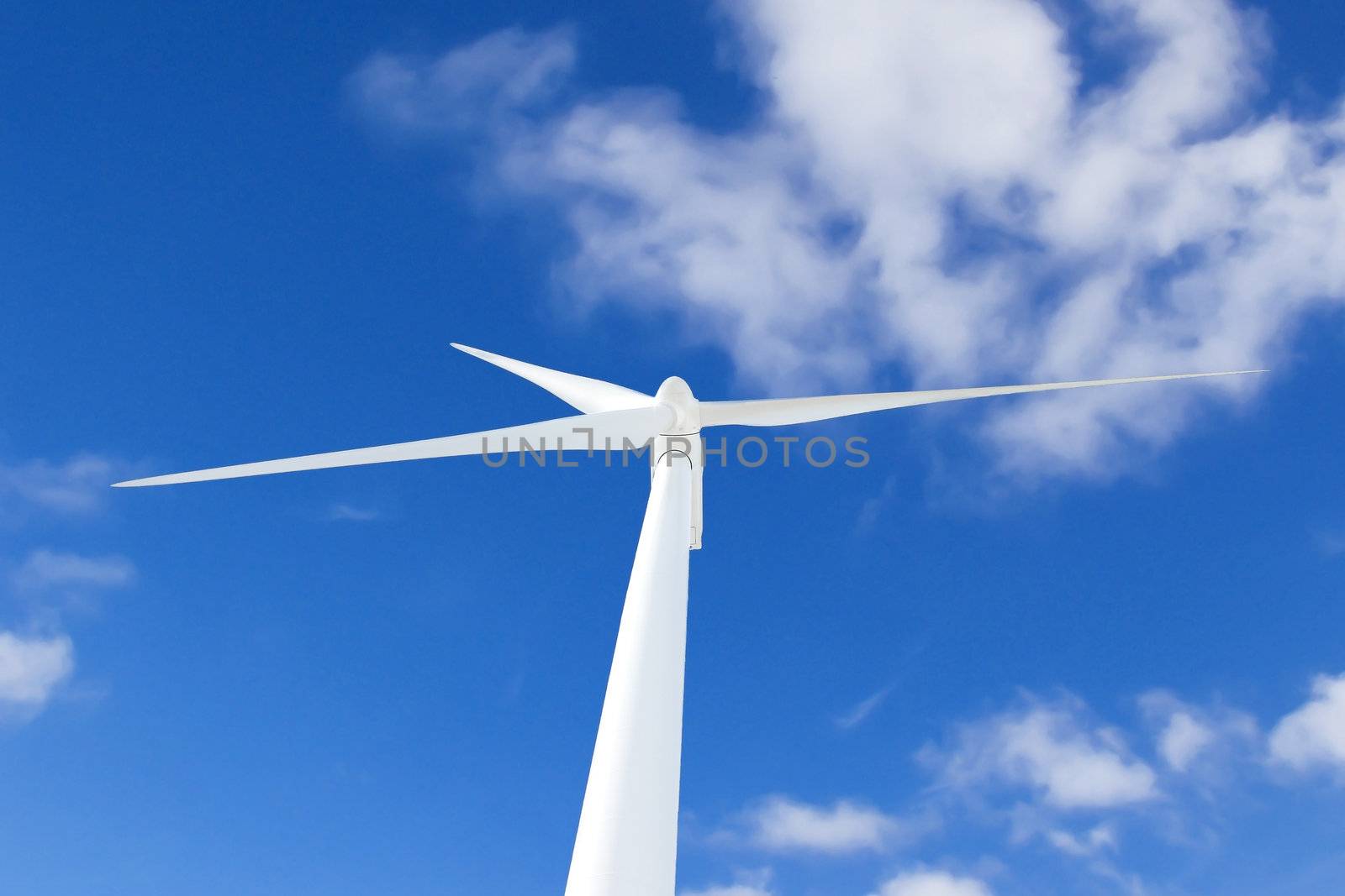 Wind turbine against blue cloudy sky. by NickNick