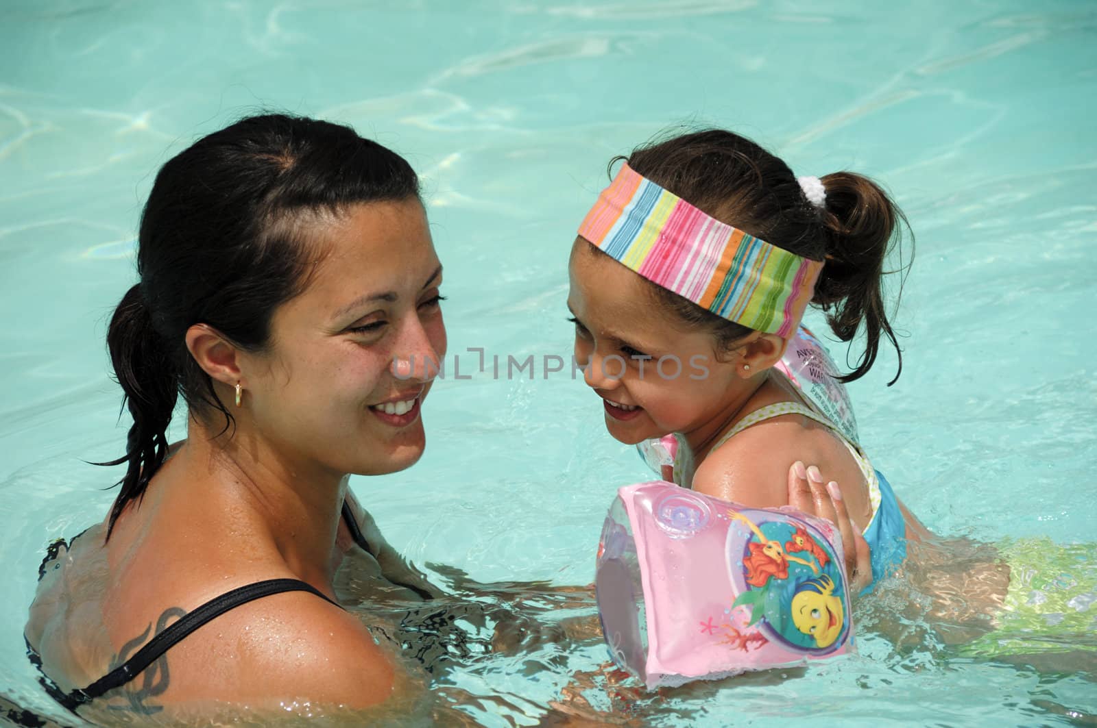 Smiling woman and child are swimming in pool