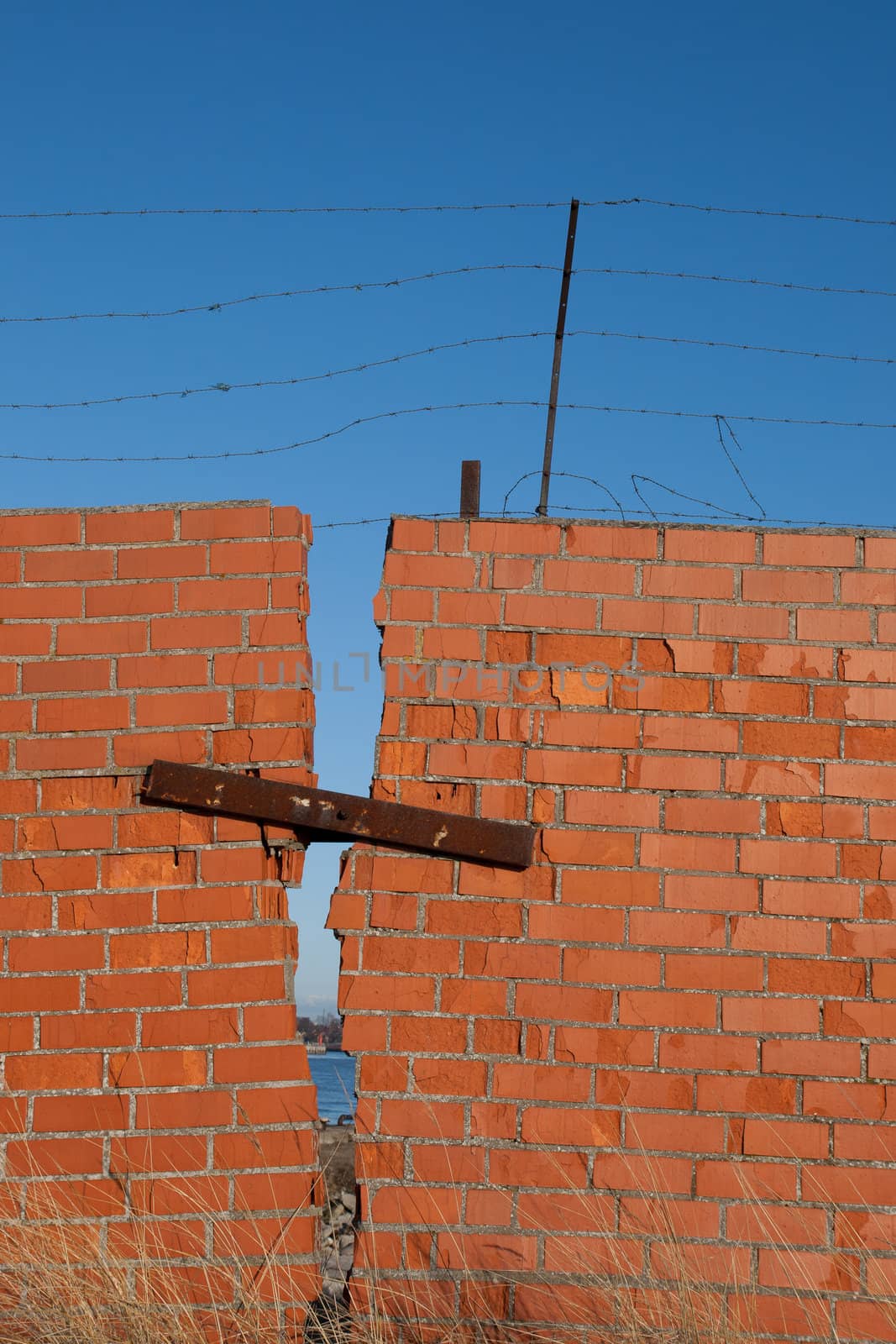 Red brick wall with rusty barbed wire