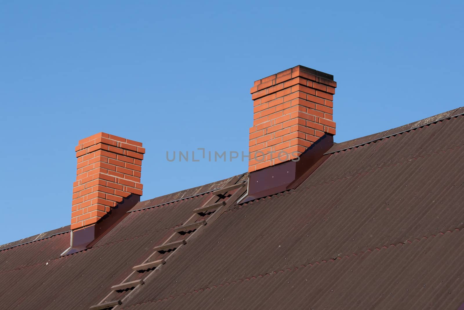 bricks chimney on the dark metal-sheet roof