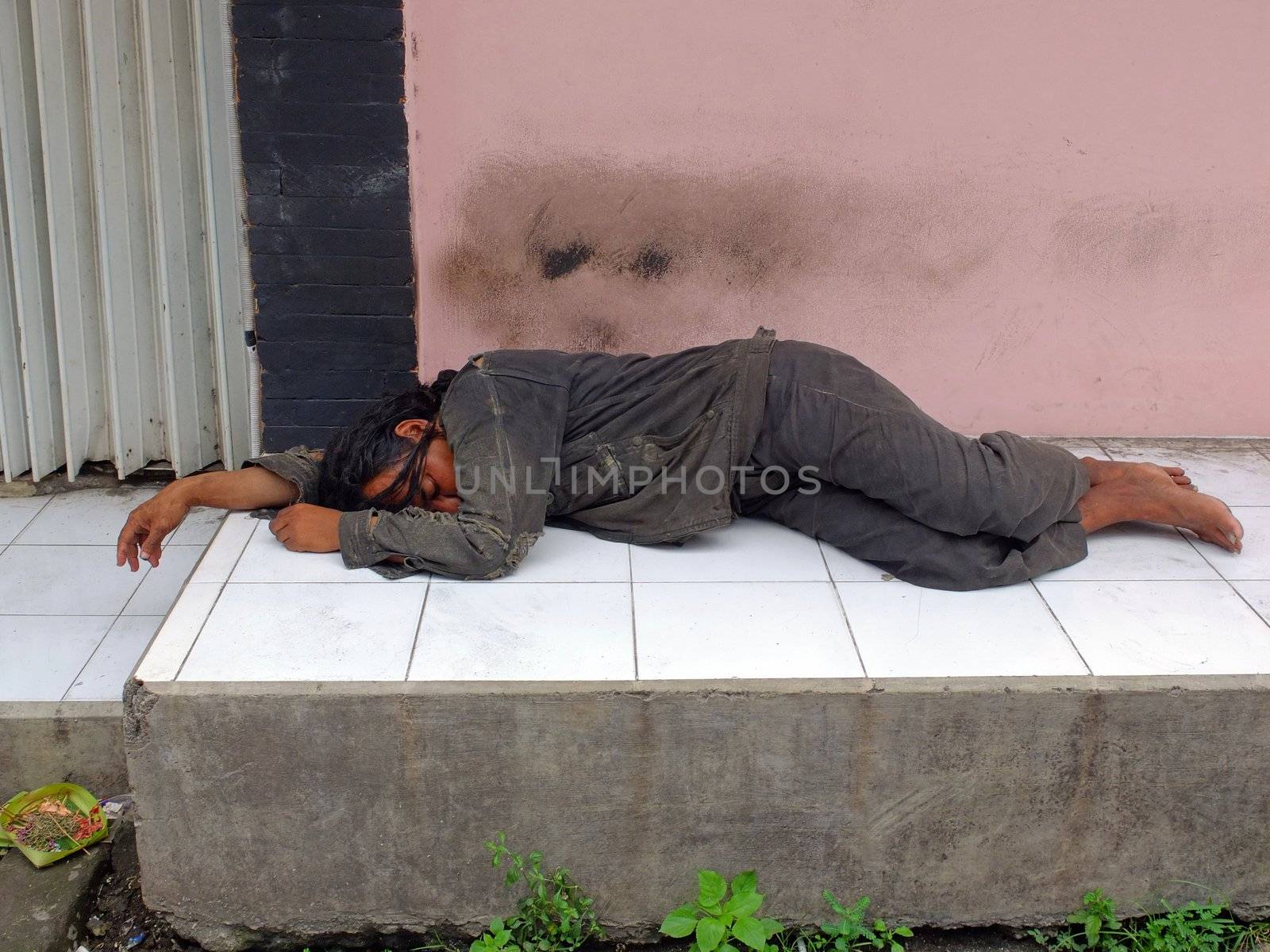 Homeless man sleeping on sidewalk, Bali, Indonesia.