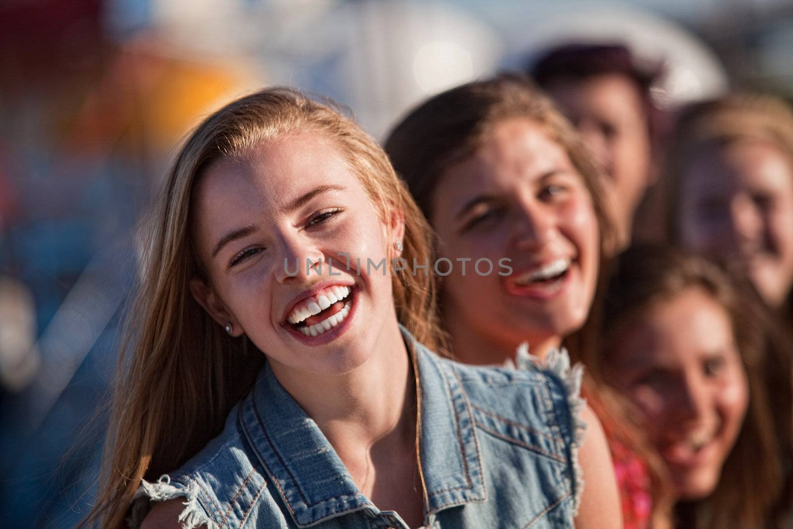 Blond teenager with friends laughing outdoors