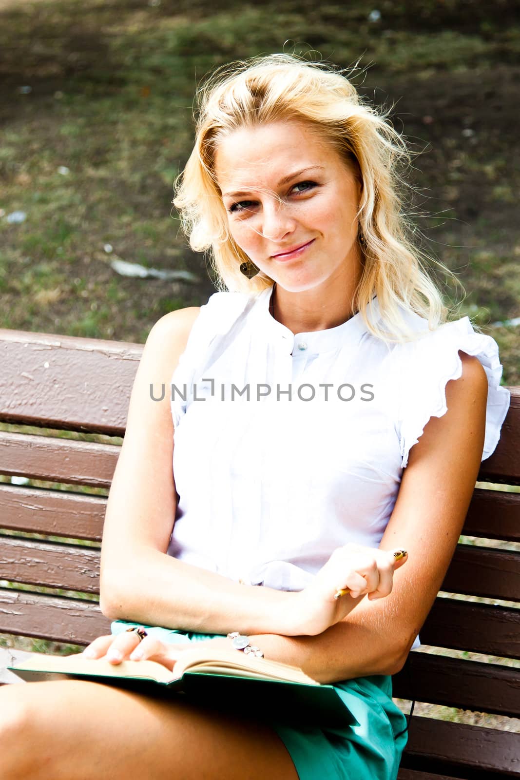 Beautiful and young woman reading a book in the park