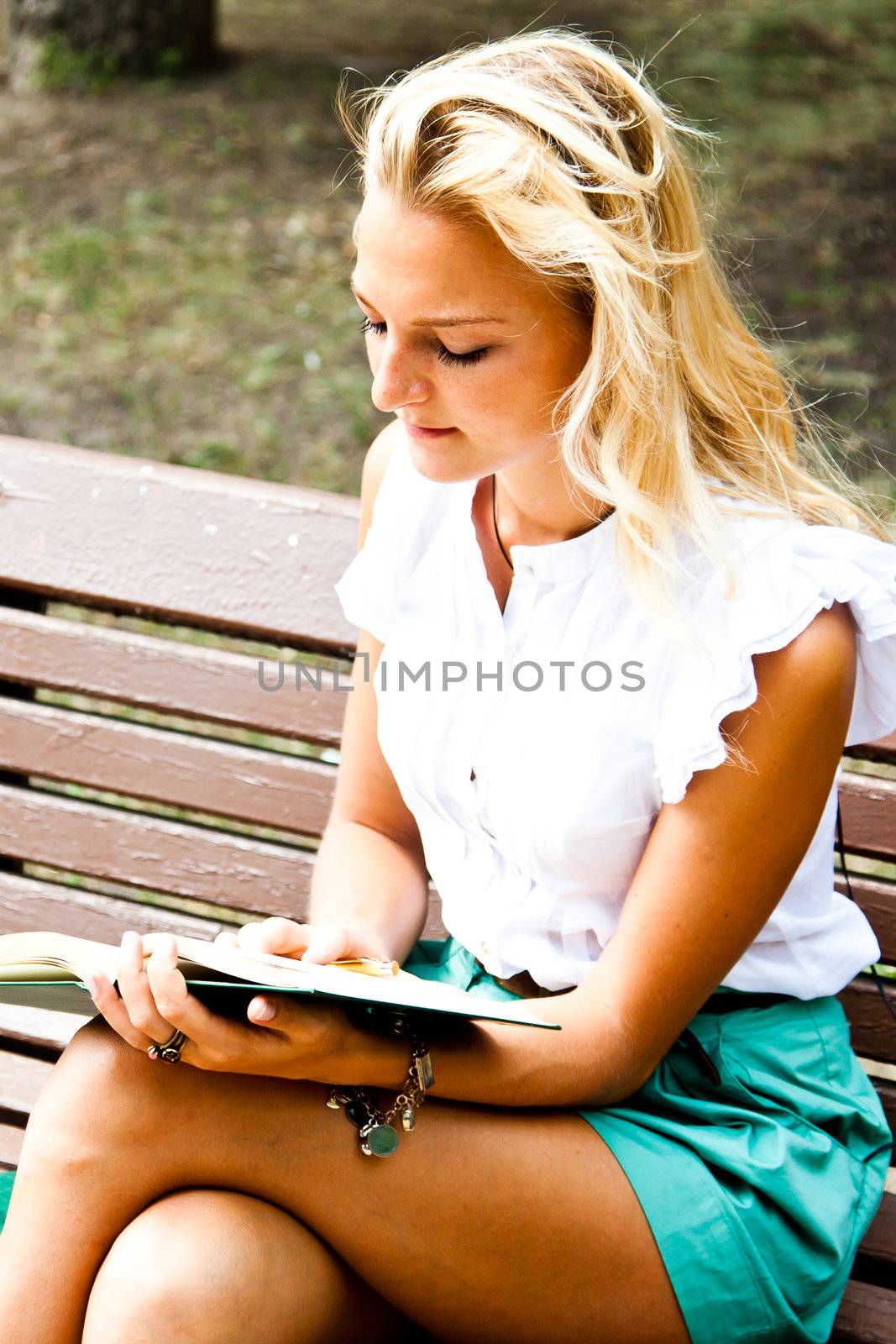 Beautiful and young woman reading a book in the park