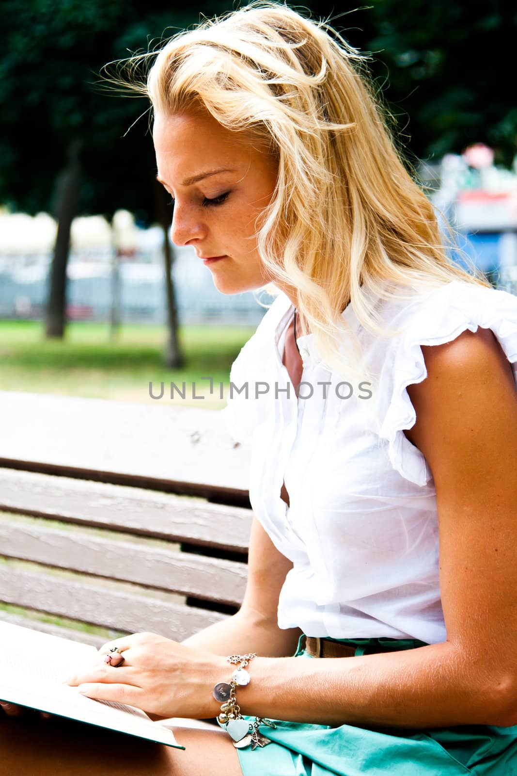 Beautiful and young woman reading a book in the park