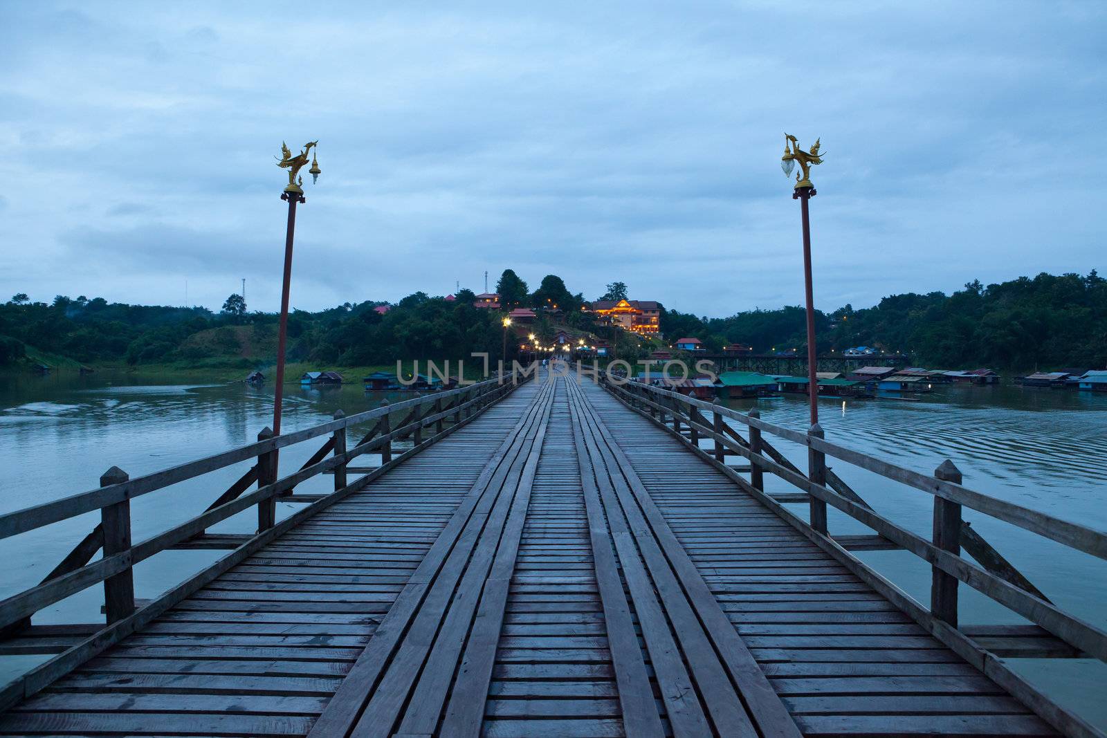 Wood bridge at night with river and mountain in Kanchanaburi Thailand