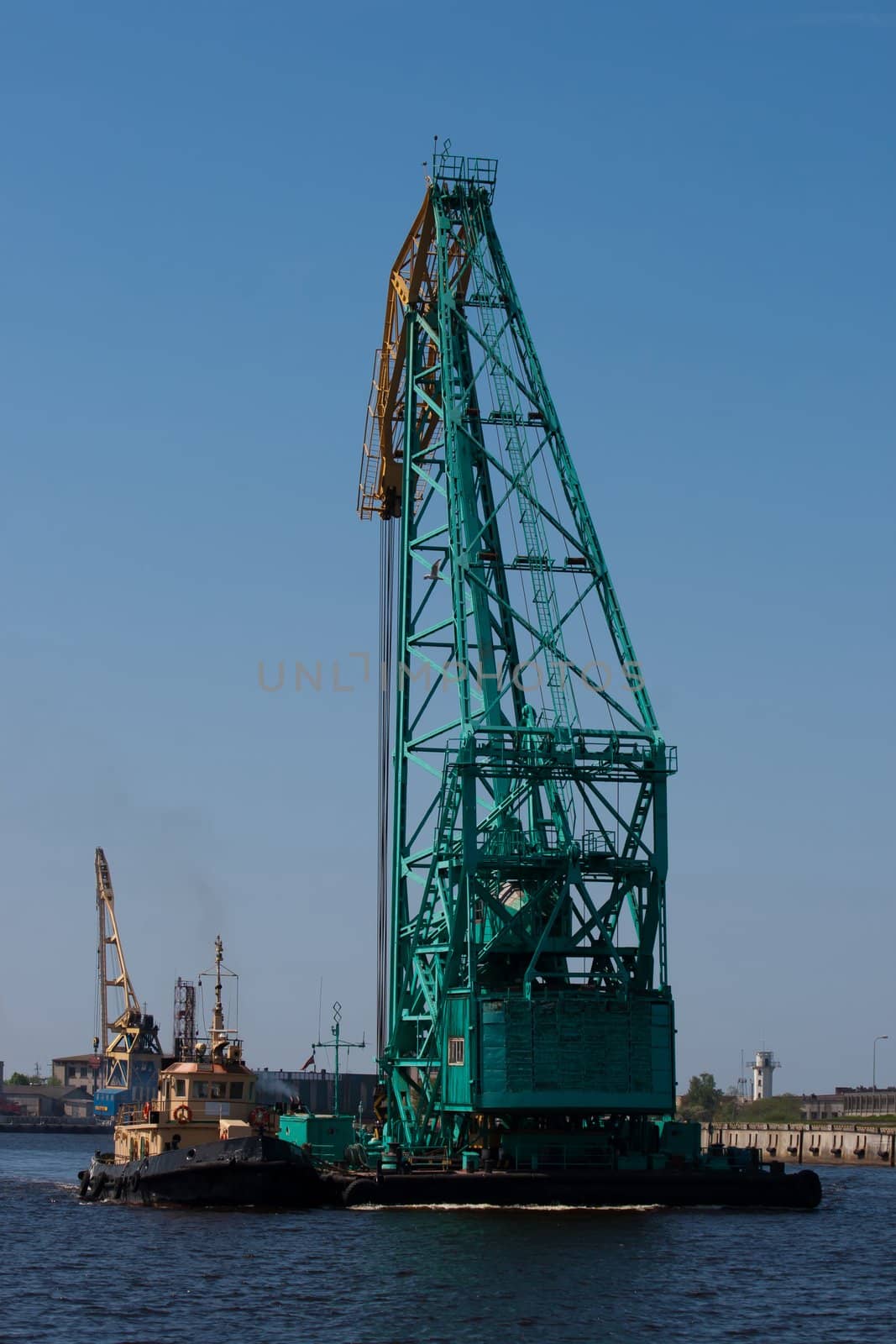 Big Floating crane pushing a small tugboat in a harbor