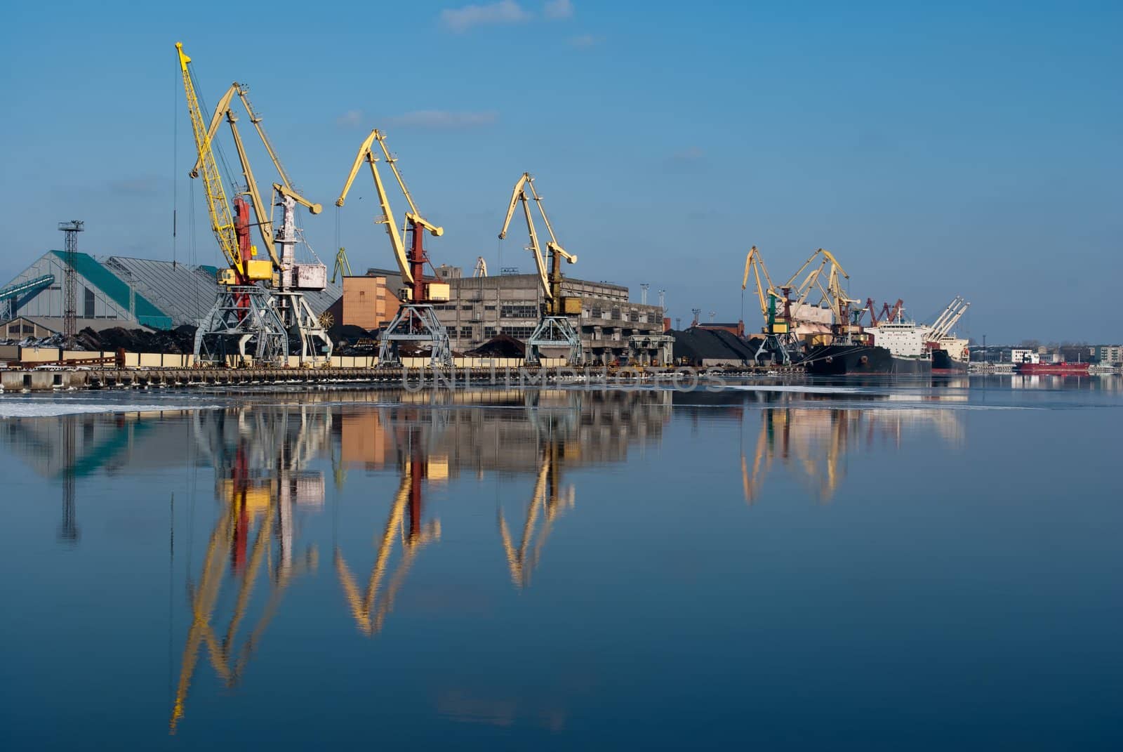 Harbor in sunshine winter day with crane reflection on water